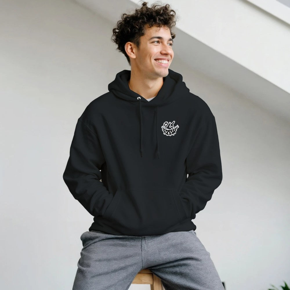 Man wearing a black hoodie with a logo, sitting on a white surface. Drum and bass