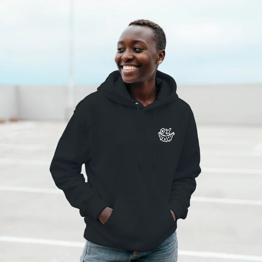 Person wearing a black hoodie with a logo, standing outdoors. Drum and bass