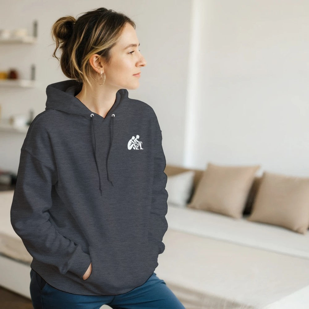 Woman wearing a dark gray hoodie with a logo in a living room setting