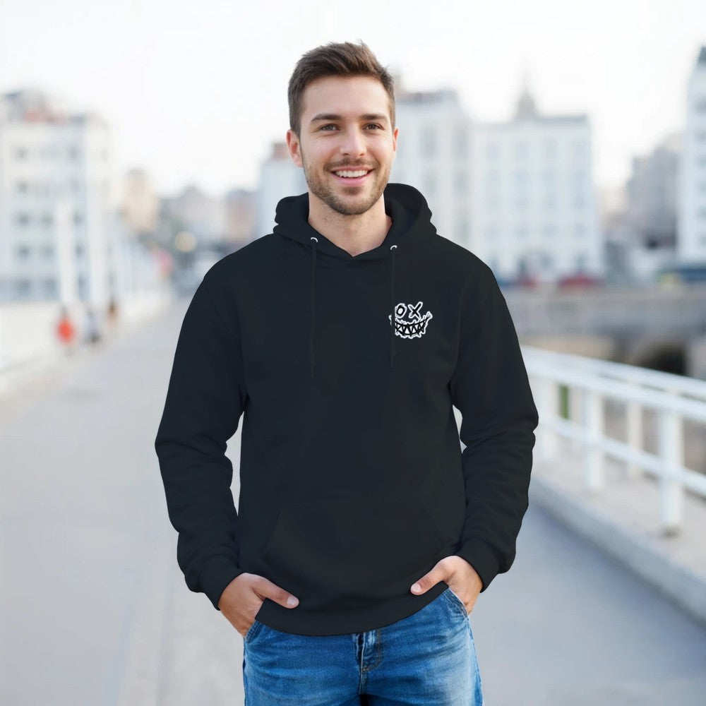 Man wearing a black hoodie with a logo, standing outdoors on a blurred city background. Drum and bass