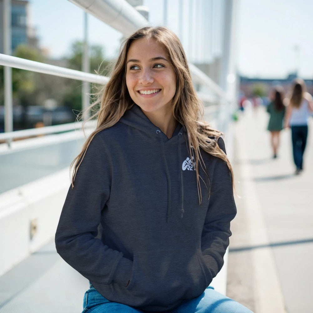Woman wearing a navy hoodie with a logo, sitting outdoors on a sunny day.